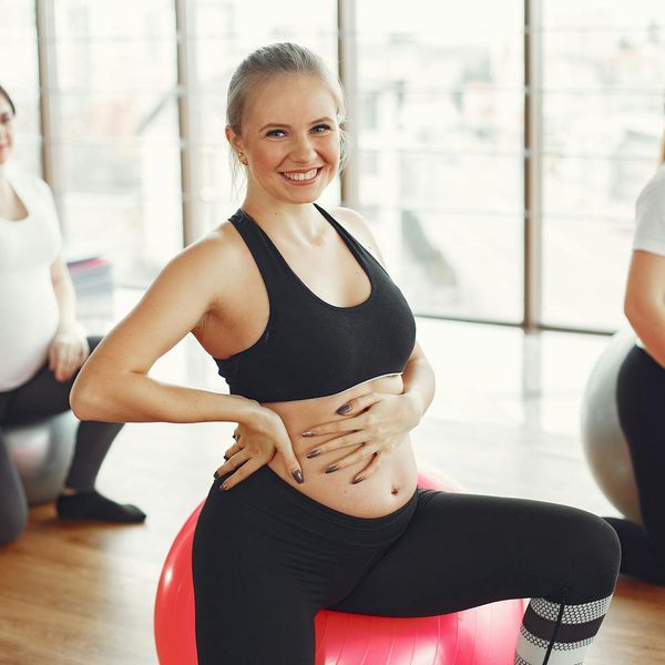 Group of diverse pregnant women smiling during a yoga class.